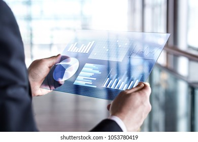 Transparent futuristic tablet. Business man using virtual touch screen. Modern mobile technology in accounting, finance, data and analytics. Internet of things (IOT) and augmented reality concept. - Powered by Shutterstock