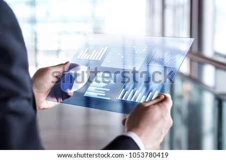 Transparent futuristic tablet. Business man using virtual touch screen. Modern mobile technology in accounting, finance, data and analytics. Internet of things (IOT) and augmented reality concept.