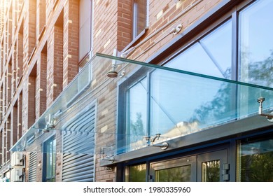 Transparent Glass Awning Over Front Door Of Multistory Brick Apartment Building