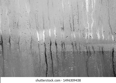 Transparent Glass with drops of water and can see through the glass outside but it is not clear. Vapour or steam on mirror when raining
