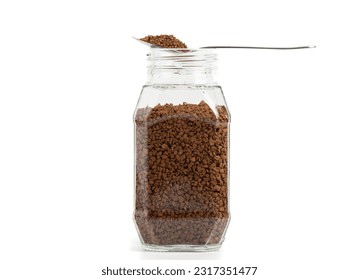 Transparent glass jar with instant granulated coffee on a white background. Spoon with instant coffee on an open coffee can. Copy space.
