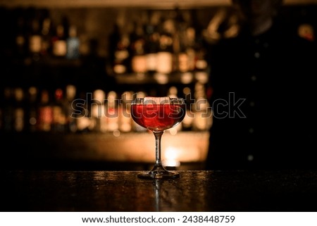 Transparent glass on a stem filled with a cocktail stands on the bar counter