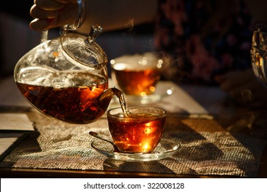 From Transparent Glass Teapot Pour Black Tea In Glass Mug, Glows In The Sun The Last Rays