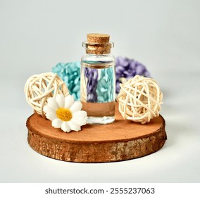 Transparent glass vial bottle container with brown cork stopper lid on wooden coaster with flowers and rattan ball decoration isolated on white background. - Powered by Shutterstock