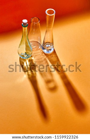 A transparent glasses empty stand on a duotone red yellow paper background with soft shadows. The Chemistry Lab. Various glass chemistry lab equipment