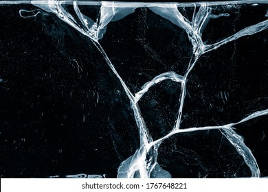 Transparent ice texture background. Textured frosty surface of ice blocks with cracks against black.