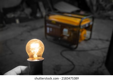 A transparent incandescent lamp glows brightly close-up against the background of a yellow gasoline electric generator in the dark