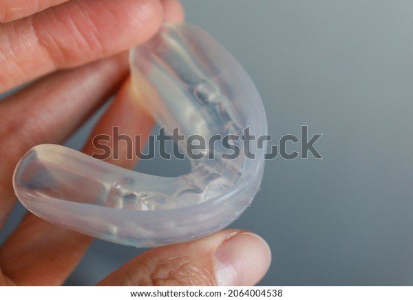 transparent mouth guard made\
of silicone, for straightening teeth in children, in a girl\'s hand,\
in daylight. Hygiene, dental care, occlusion correction, new\
technologies