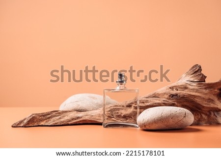 Transparent perfume bottle near the aged weathered wooden snag and stones. Perfume with woody notes concept. Background with copy space. Сток-фото © 