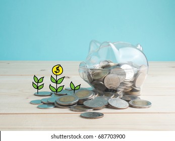 Transparent piggy bank filled with coins on wood background.Saving investment colorful concept.Watering can and money tree drawn concept for business investment, savings and making money.