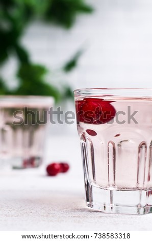 Transparent pink drink with cranberry in the glass on a light background. Selective focus.