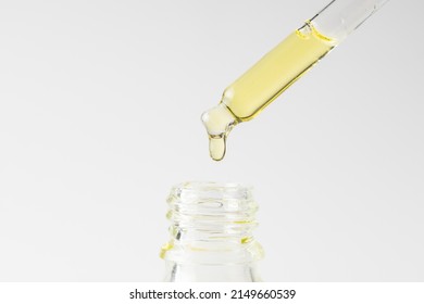 Transparent Pipette With Cosmetic Liquid On A White Background. Essential Oil Dropper Close Up.