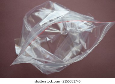 Transparent plastic bag with zip clasp on a dark background. The clasp is open.