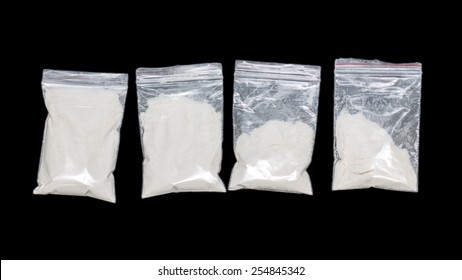 Transparent plastic bags with white powder isolated on black background
