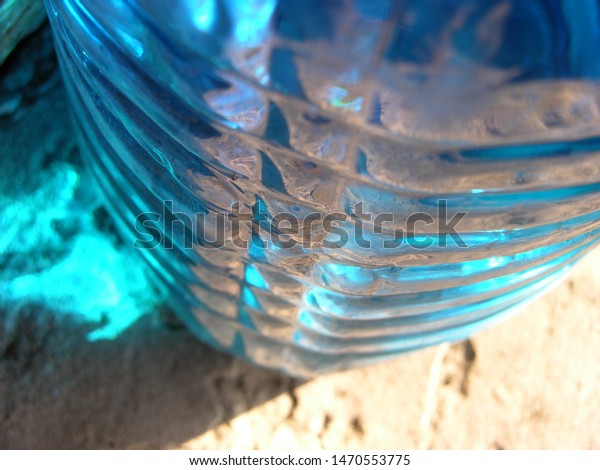 Transparent plastic canister with blue automobile liquid\
(blue non-freezing liquid) on the porch on the threshold of the\
house. on the bottle are located transverse swathe of. game of\
light spots. 