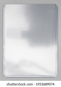Transparent Plastic Card Toploader Case On White Paper Background, Gaming Or Trading Card Placeholder With Nice Light Reflection.