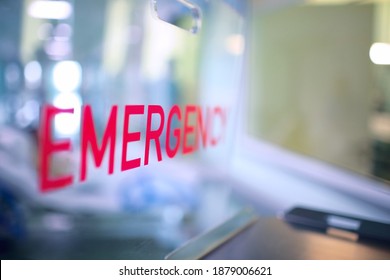 Transparent plastic divider on the reception desk in the hospital admission department with red lettering emergency. - Shutterstock ID 1879006621