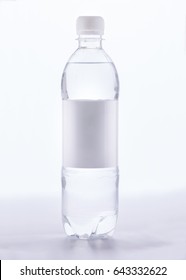 A transparent plastic half liter bottle with a white cap and a white blank paper label around the middle of the bottle, photo with the original shadow