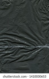 Transparent plastic wrap on the black background. Plastic bag texture. Reusable trash and waste.