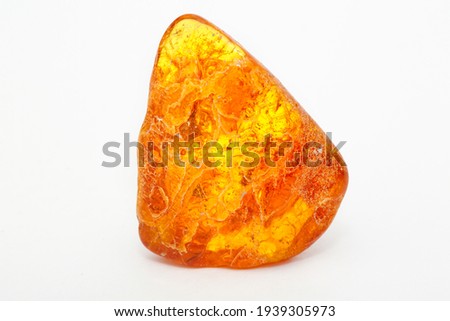 A transparent polished piece of yellow amber on a white background. Sun stone. Natural mineral material for jewelry. Amber texture. Copal. Multicolored yellow background. Ancient fossil resin