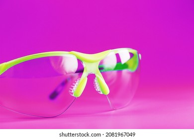 Transparent Polycarbonate Safety Glasses On A Pink Background. Reliable Eye Protection, Close-up