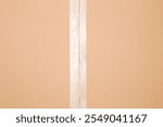 Transparent scotch tape on closed brown carton pack. Closeup. Top view.