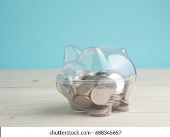 transparent see through piggy bank filled with coins on wood background.Saving investment colorful concept.