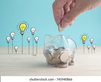 transparent see through piggy bank filled with coins on wood background.Saving investment colorful concept.Hand putting coin into pink piggy bank.