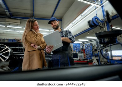 Transparent service: Mechanic uses a tablet to share repair details and costs with a client, ensuring clarity in automotive maintenance. - Powered by Shutterstock