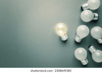 Transparent small light bulb glowing in the group of the white light bulbs, different and original idea