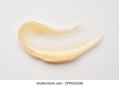 Transparent smear and texture of golden cosmetic gel on a white background.