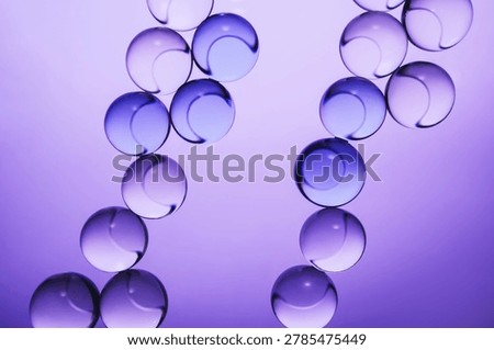 Transparent spheres creating an abstract chains pattern with reflections on purple background
