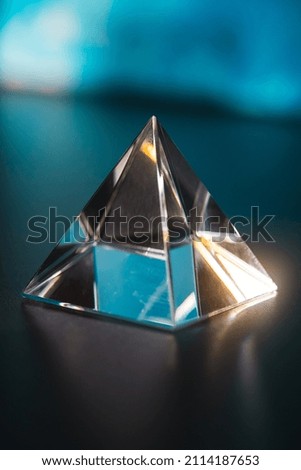 Transparent triangular prism on the table. Prism for design. Prism in the shape of a pyramid