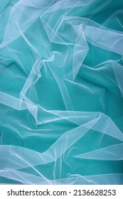 transparent tulle fabric arranged in soft folds on a green background, selective focus