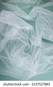 transparent tulle fabric arranged in soft folds on a green background, selective focus - Shutterstock ID 2137527883
