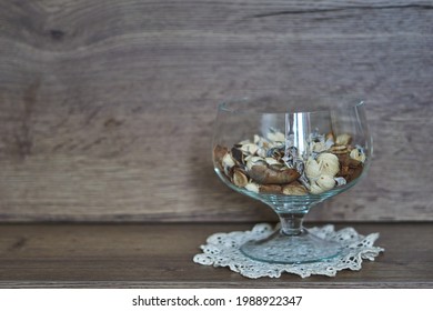 Transparent vase with white, beige and brown dry flowers, on a wooden background, aromatherapy.