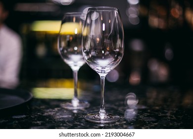 Transparent wine glasses with bokeh of bright lights. Glasses on a light background, in a warm tone. Postcard for holidays and dinners. - Powered by Shutterstock