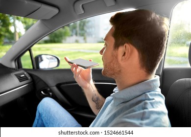 Transport, Business And Technology Concept - Male Passenger Using Voice Command Recorder On Smartphone On Back Seat Of Taxi Car