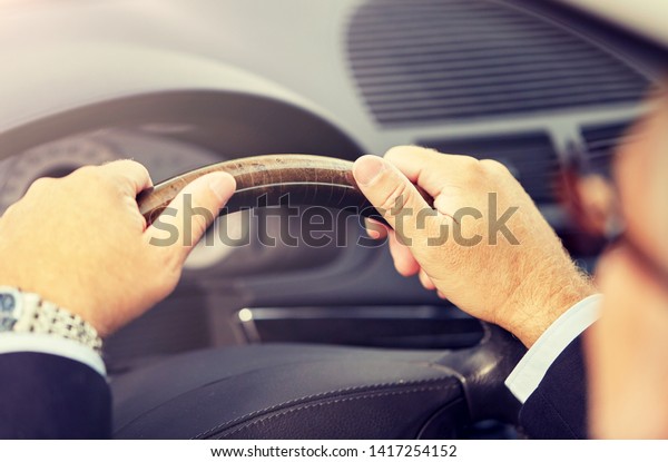 transport, business trip and people concept - senior\
businessman hands driving\
car
