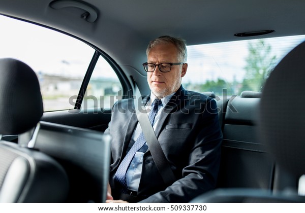 transport, business trip, safety\
and people concept - senior businessman driving on car back\
seat