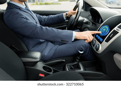 Transport, Business Trip, Technology And People Concept - Close Up Of Young Man In Suit Driving Car And Adjusting Car Eco Mode System Settings On Dashboard Computer Screen