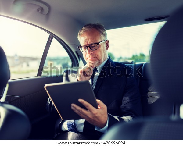 transport, business trip, technology and people
concept - senior businessman with tablet pc computer driving on car
back seat