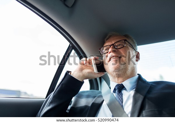 transport, business trip, technology and people\
concept - senior businessman calling on smartphone and driving on\
car back seat