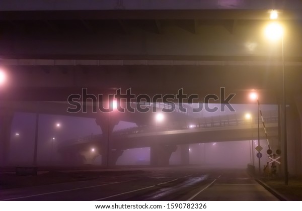 Transport concept. Car interchange in the\
fog. Railway crossing. Rail and road on a cloudy evening. Highways\
in the fog. Deserted highways and\
crossings.