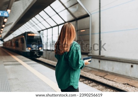 Transport concept, Traveler. Young Caucasian woman waiting train at railway platform for arrival and departure. Travel to vacation by train. High speed train in motion on the railway station