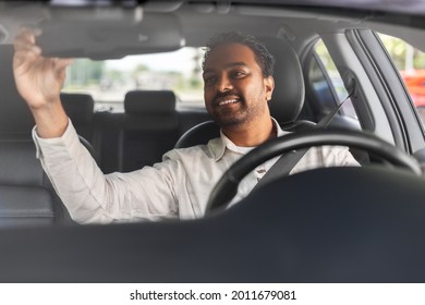 transport, driving and people concept - happy smiling indian man or driver adjusting mirror in car