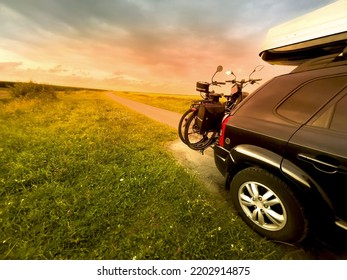 Transport e bikes by car. A roof rack stores luggage on the journey. Sunset. SUV with gas tank.	