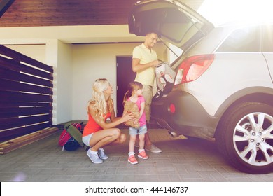 Transport, Leisure, Travel, Road Trip And People Concept - Happy Family Packing Things Into Car At Home Parking