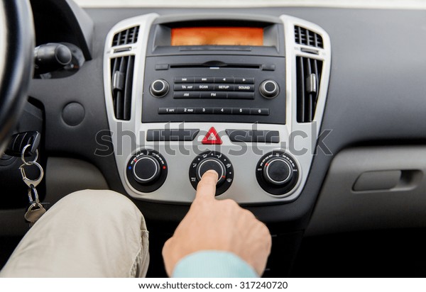 transport, road\
trip, car driving, technology and people concept - close up of male\
hand using climate control in\
car