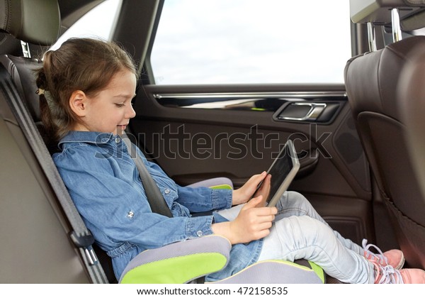 transport,\
road trip, travel, technology and people concept - happy little\
girl with tablet pc driving in car safety\
seat